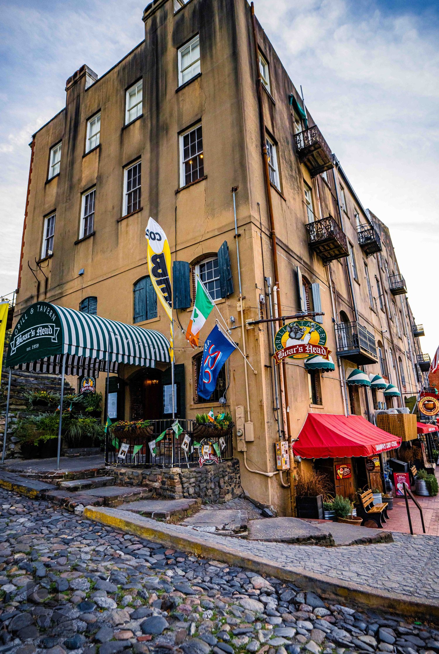 Historic cobblestone street lined with colorful awnings and old buildings in Charleston's French Quarter district.