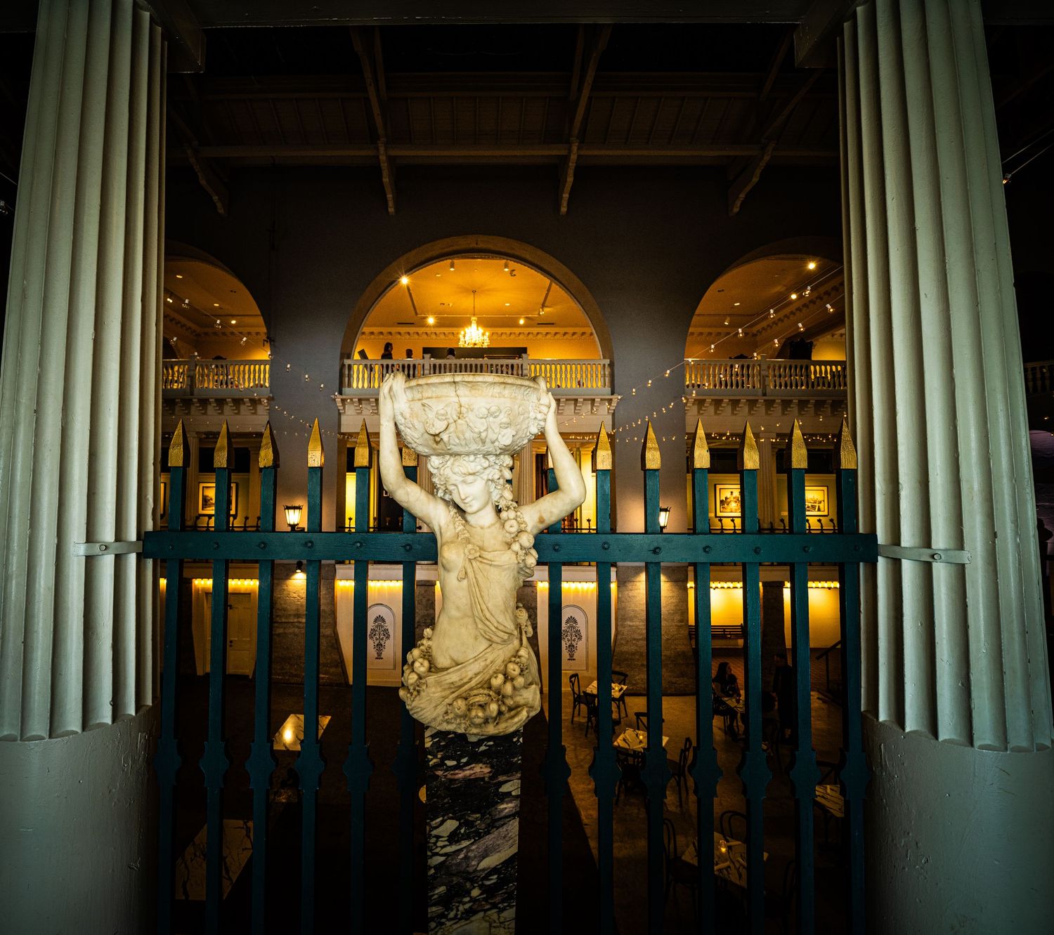 Dramatic night view of white columns and archways with illuminated classical statue.