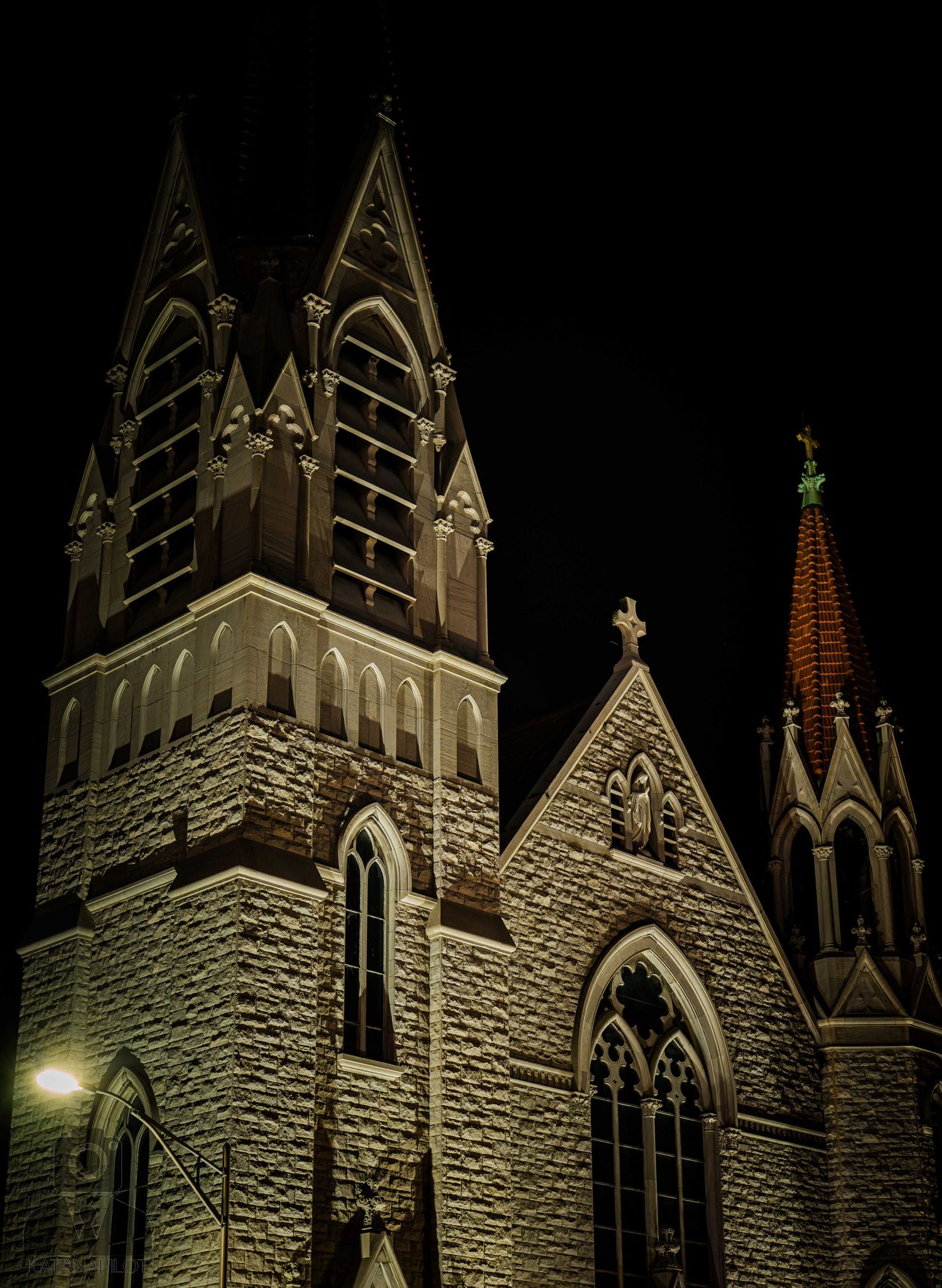 Gothic stone church illuminated at night with pointed spires and arched windows against a dark sky.