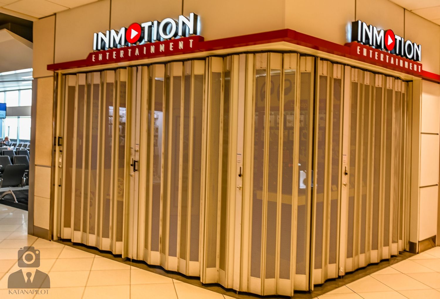 Closed InMotion electronics store with gold security gate in a shopping mall.