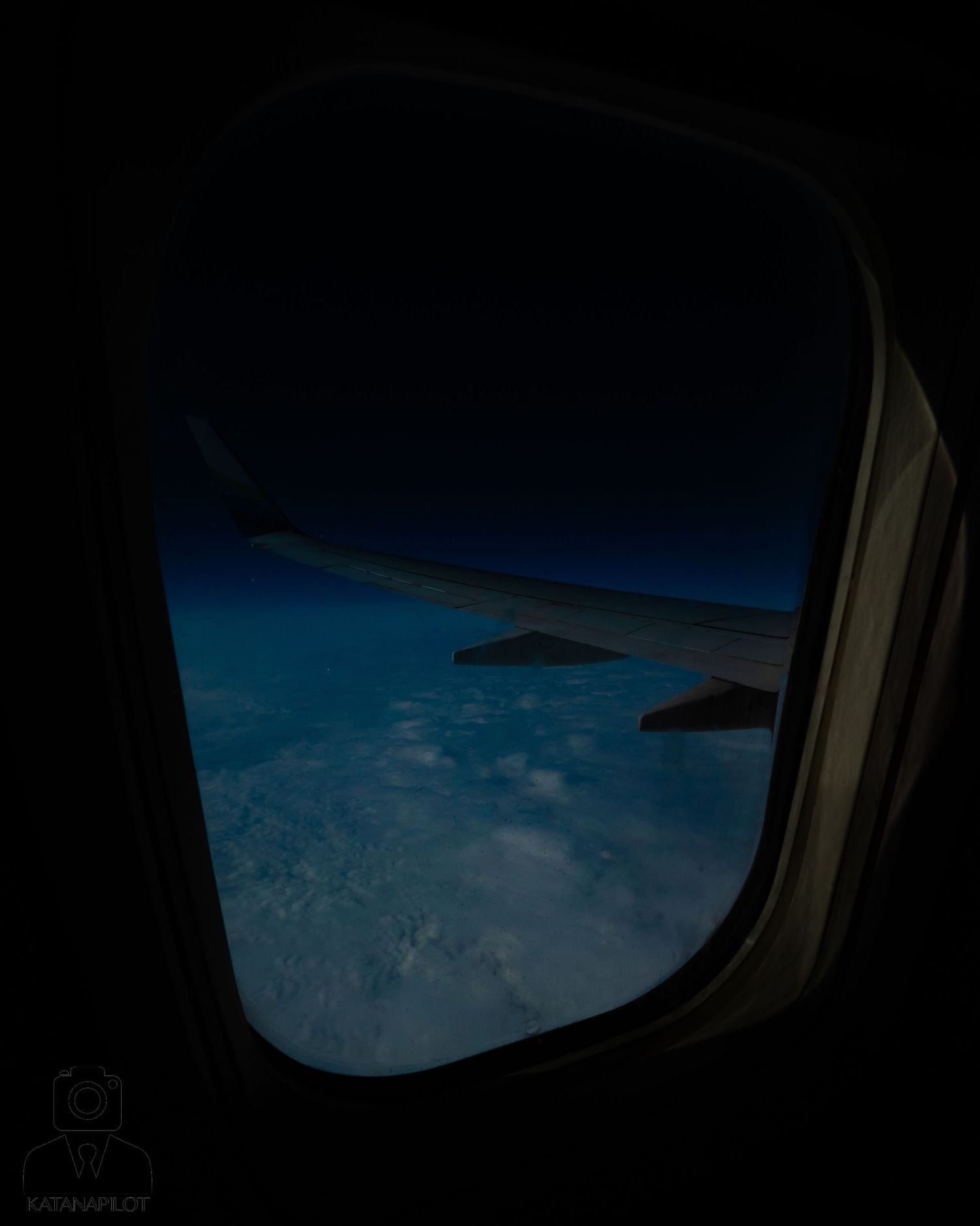 View of Earth's horizon and blue atmosphere through airplane window during flight.