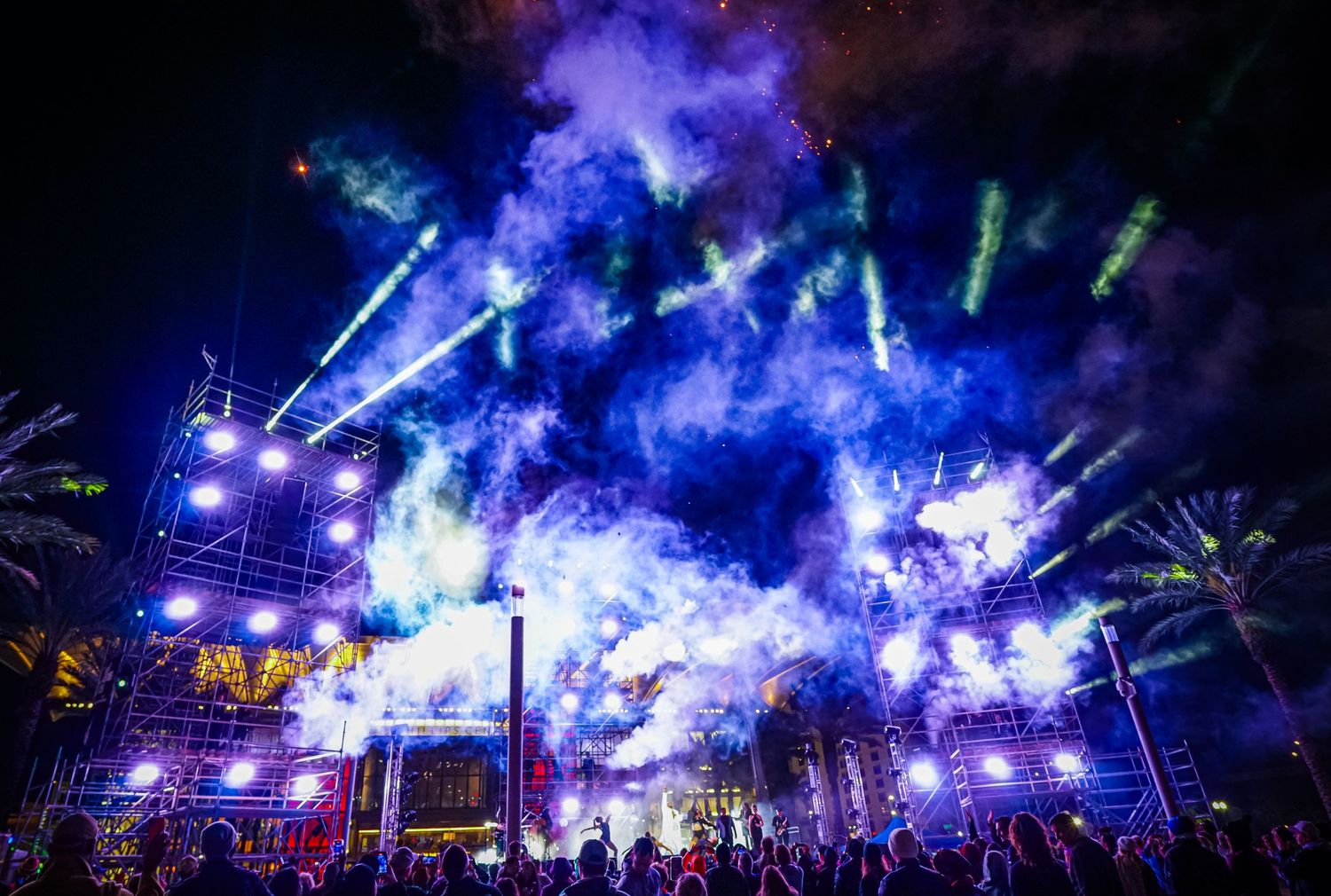 Concert venue filled with blue smoke and dramatic lighting effects during a nighttime performance.
