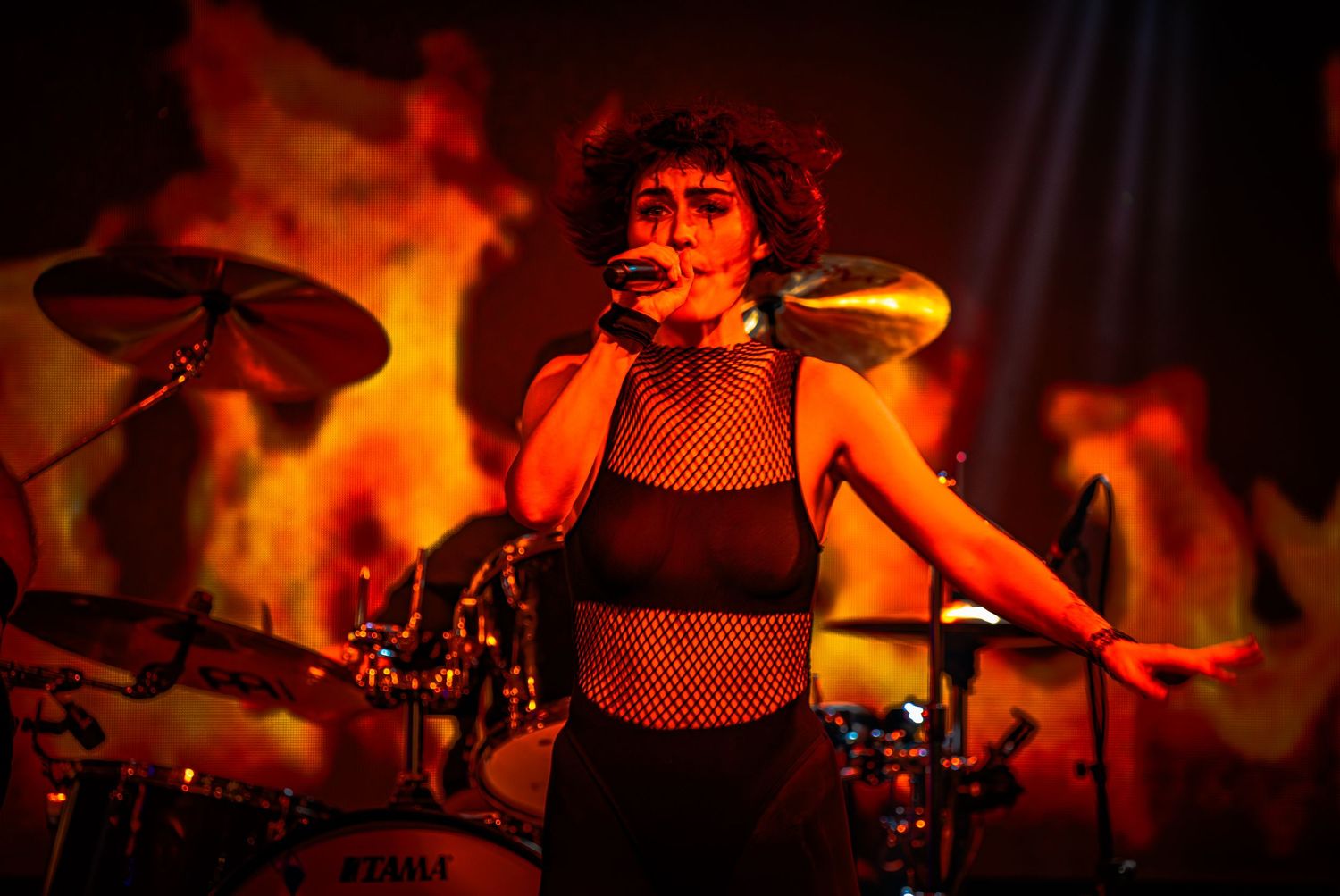 Musicians performing on stage illuminated by intense red theatrical lighting.