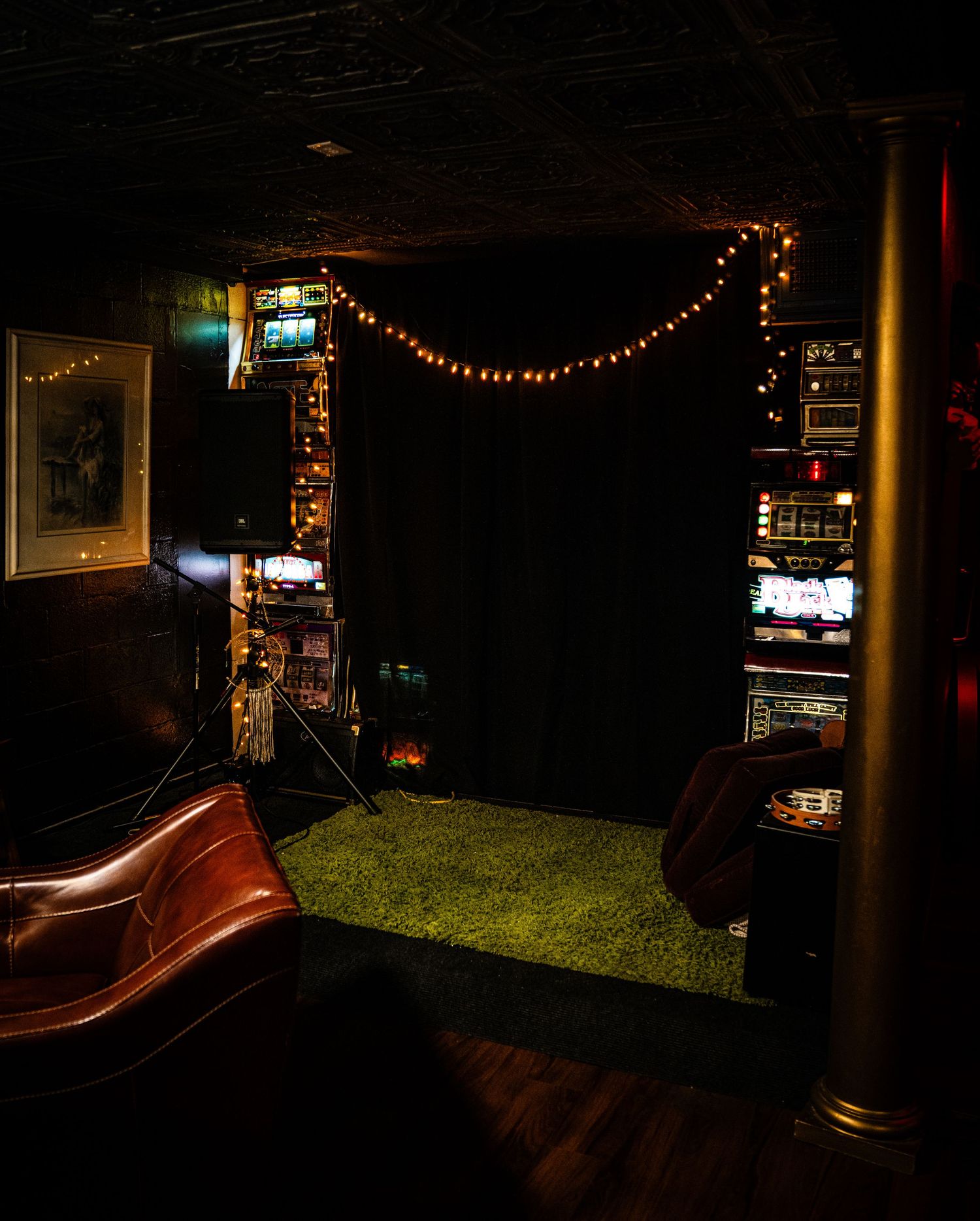 A dimly lit bar interior with string lights and dark ambiance creating a cozy atmosphere.