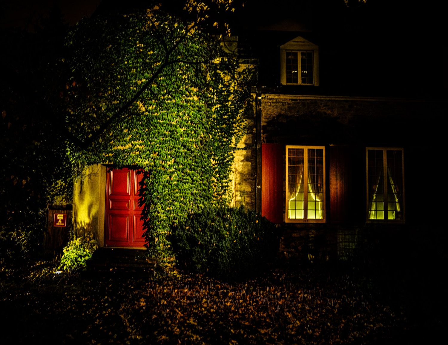 Illuminated windows and garden lights create a cozy nighttime scene at a residential property.