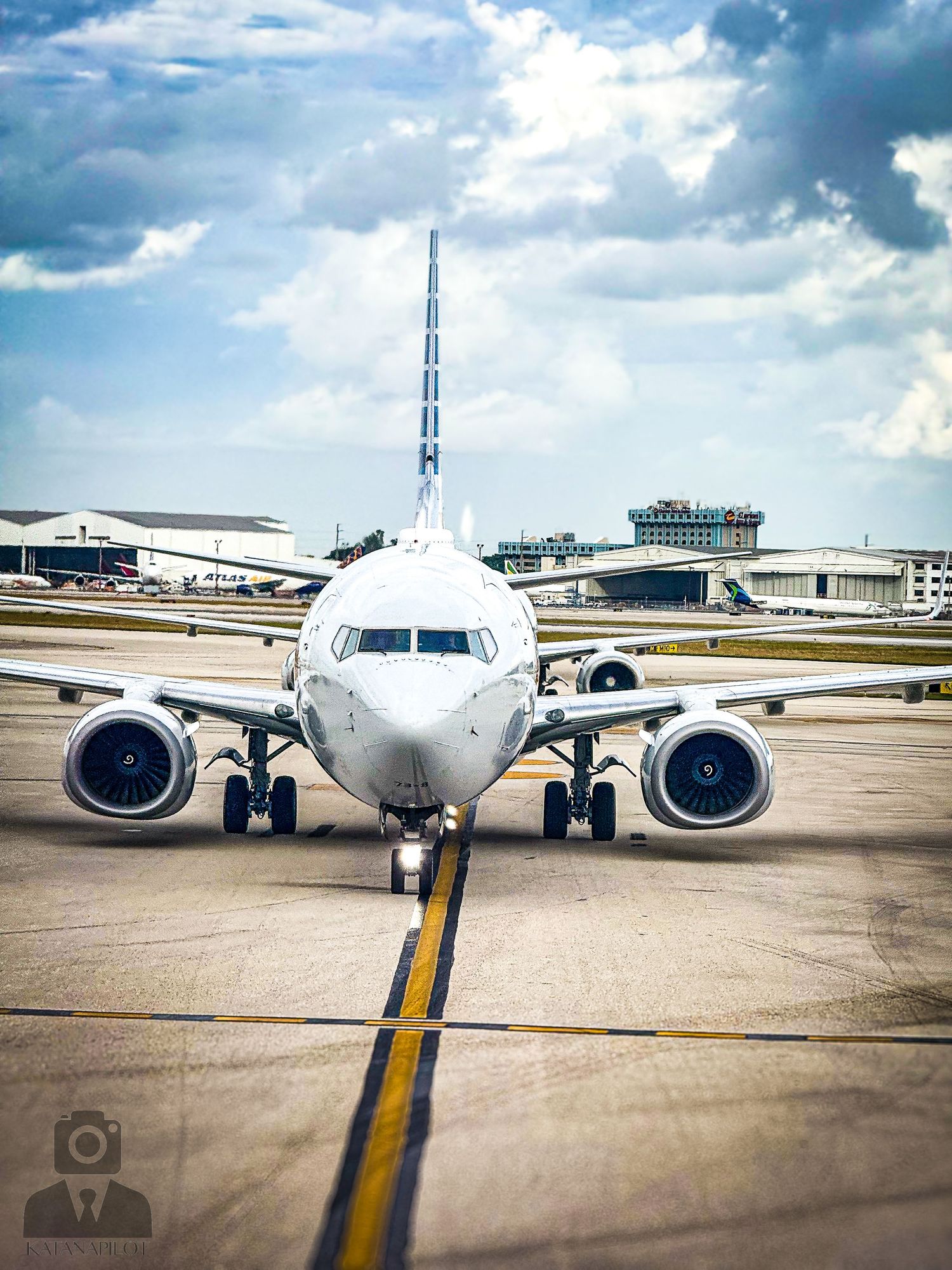 Commercial passenger jet on taxiway with dramatic cloudy sky background.