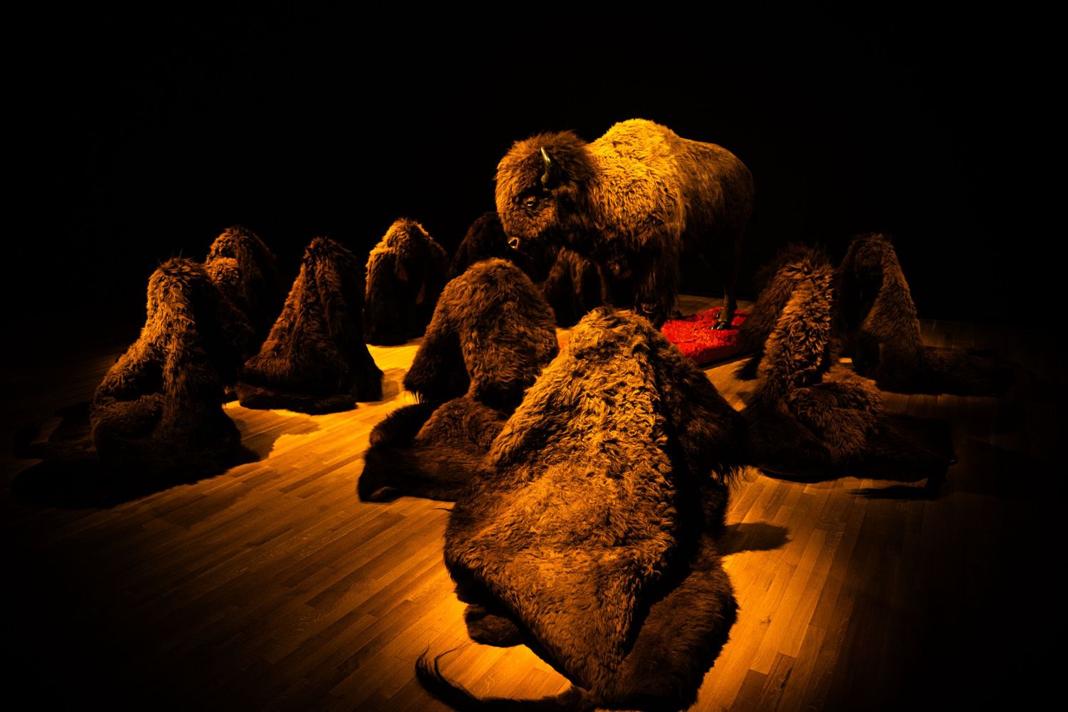 Dramatic stage performance with dancers in dark silhouettes against warm amber lighting creating a moody atmosphere.
