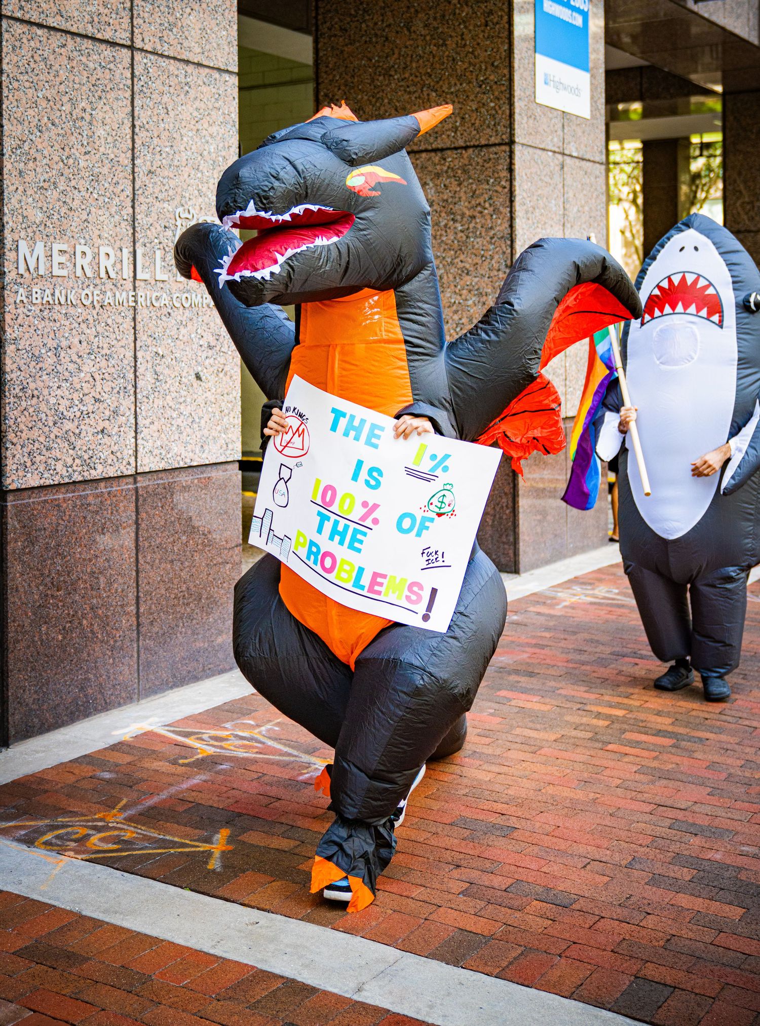 Inflatable costume performers lined up on brick pavement during a street demonstration.