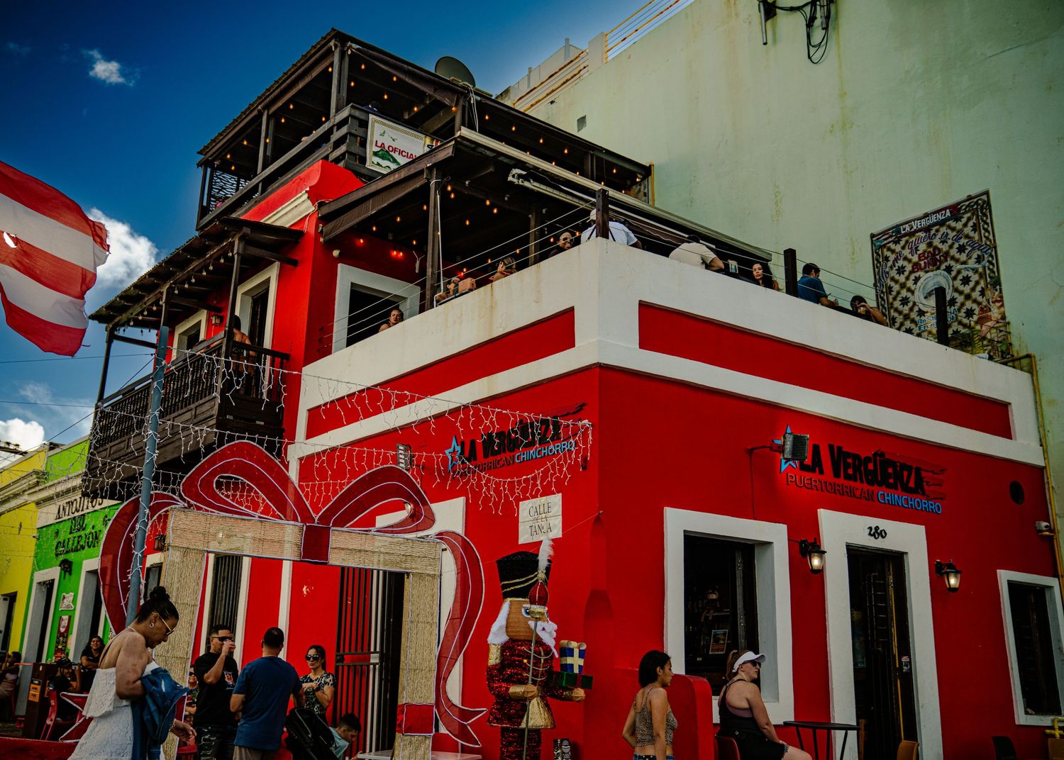 Vibrant red and white colonial building with ornate balconies in Old San Juan, Puerto Rico against a blue sky.
