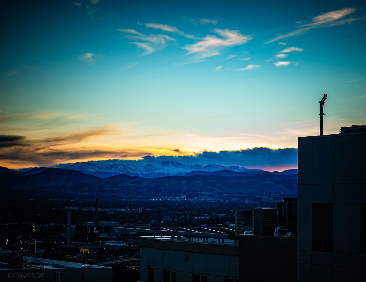 Panoramic timelapse sequence of a vibrant sunset over a city skyline with mountains in the background.