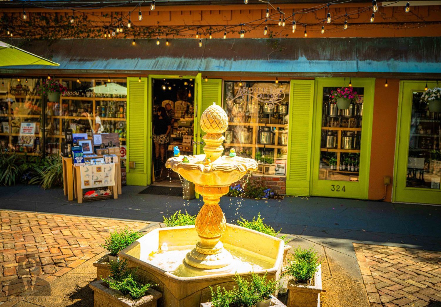A decorative water fountain with cascading tiers illuminated at night in a shopping center courtyard.