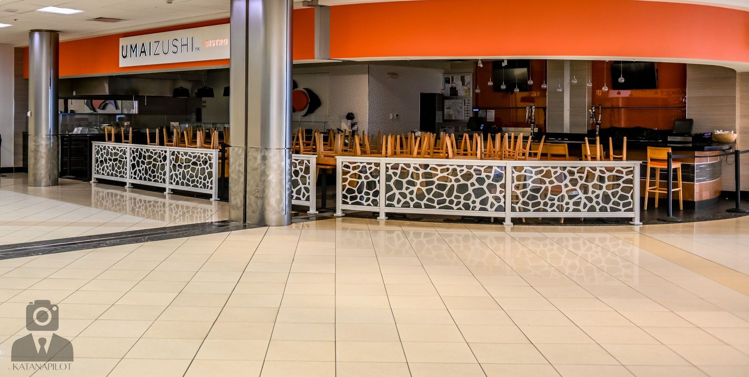 Long view of an indoor shopping mall corridor with orange accent walls and closed storefronts.