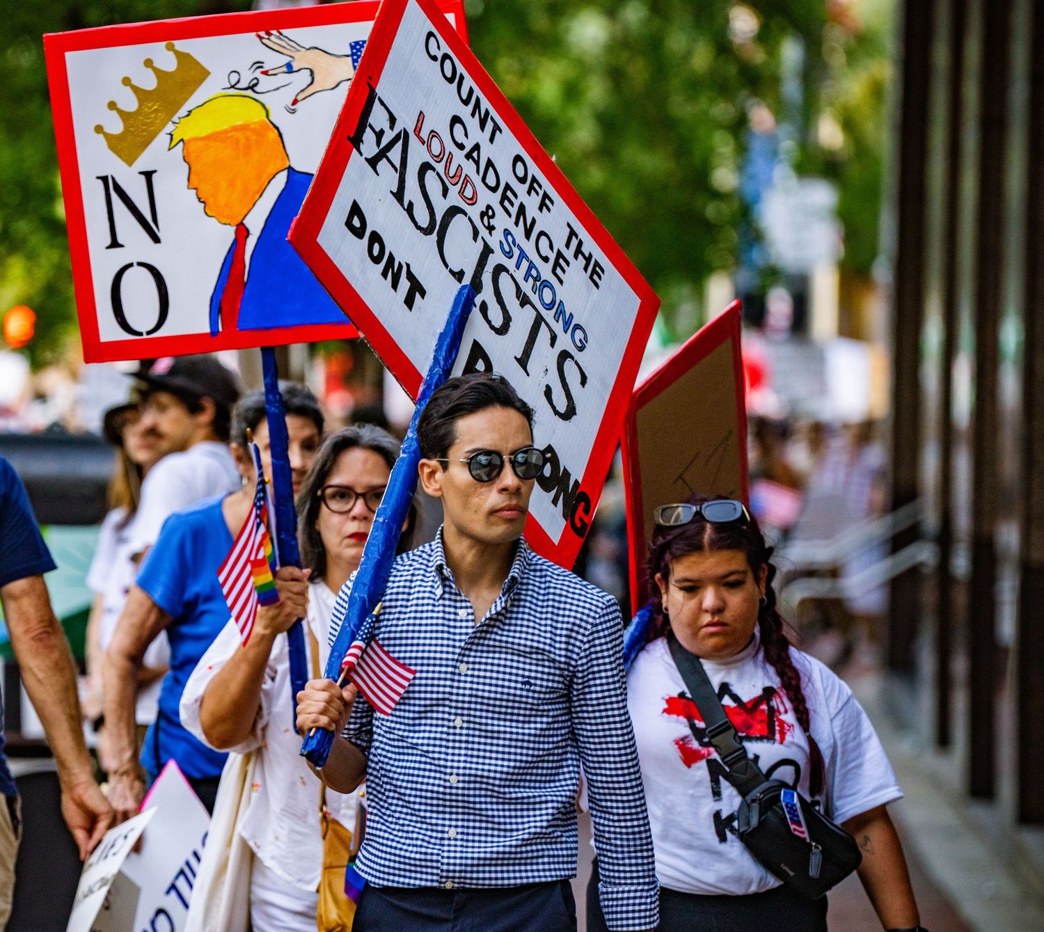 Protesters march with signs during a political demonstration on city street.