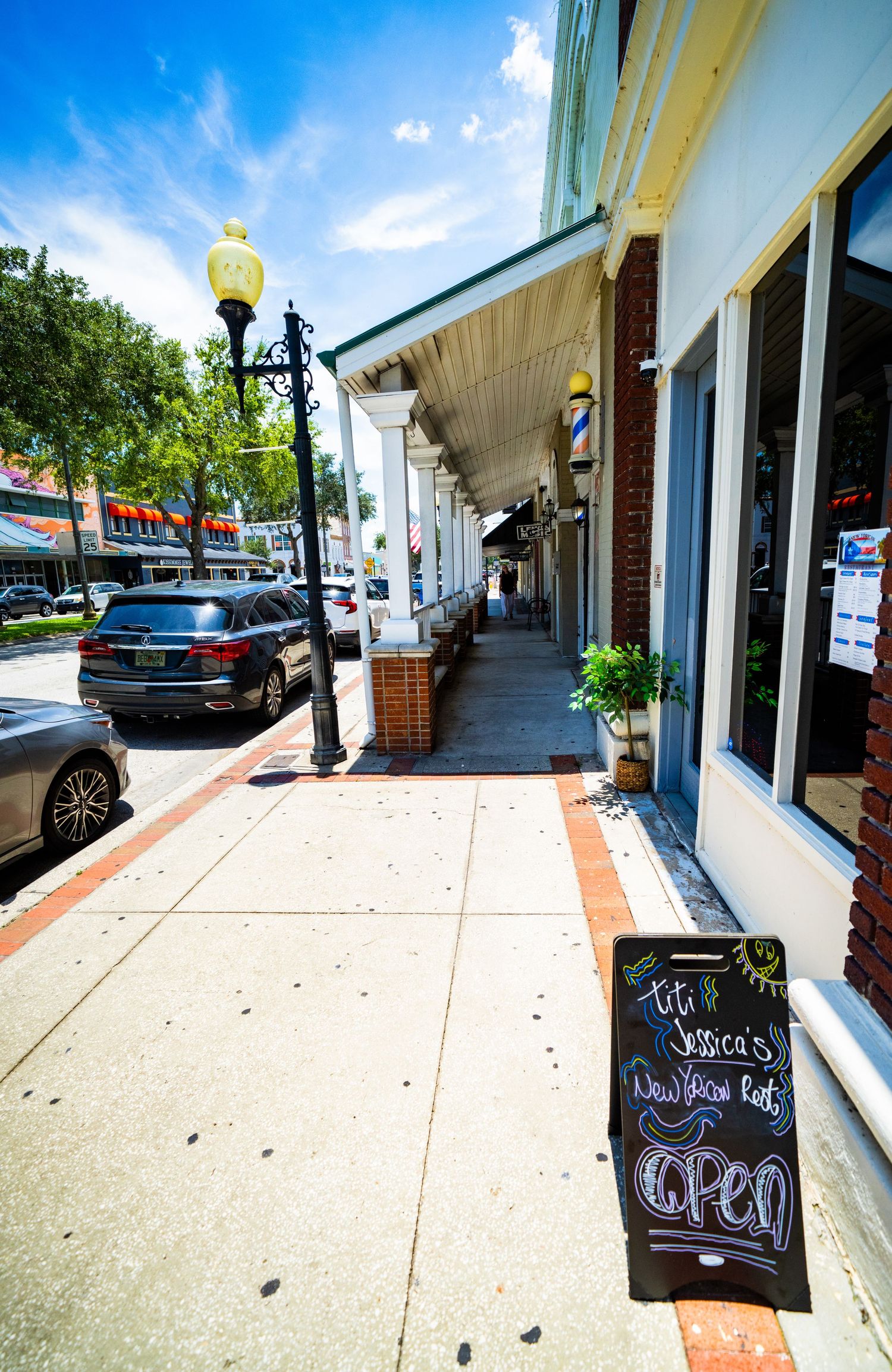 Sidewalk perspective along downtown shops with chalkboard signs and brick accents.