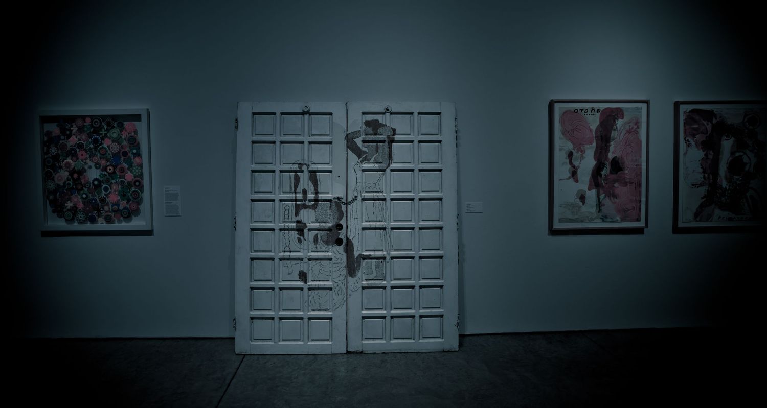 Dark art gallery with damaged white double doors flanked by abstract paintings on gray walls.