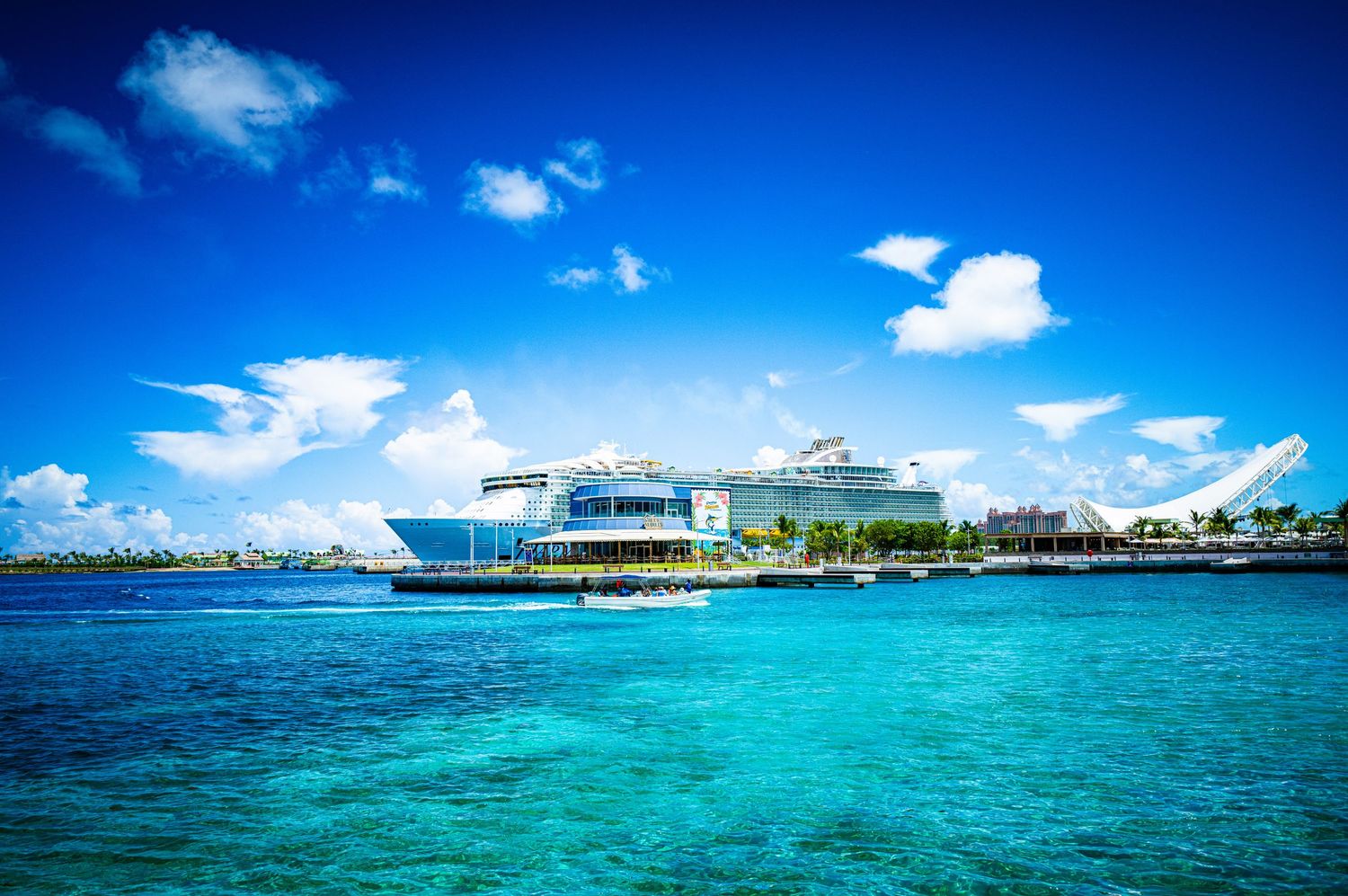 Turquoise Caribbean waters with a modern cruise terminal and ships docked under a vibrant blue sky.