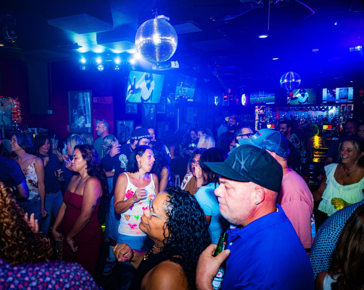 Nightclub scene with blue lighting and a crowded dance floor filled with people enjoying the music.