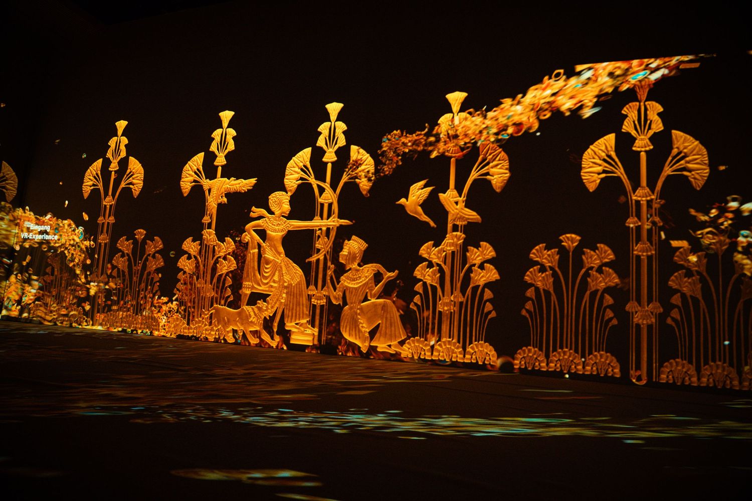 Row of illuminated golden Egyptian statues in a display.