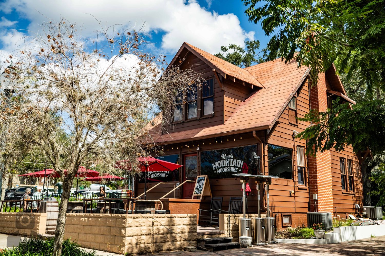 Rustic wooden lodge style building with red trim and outdoor dining area.