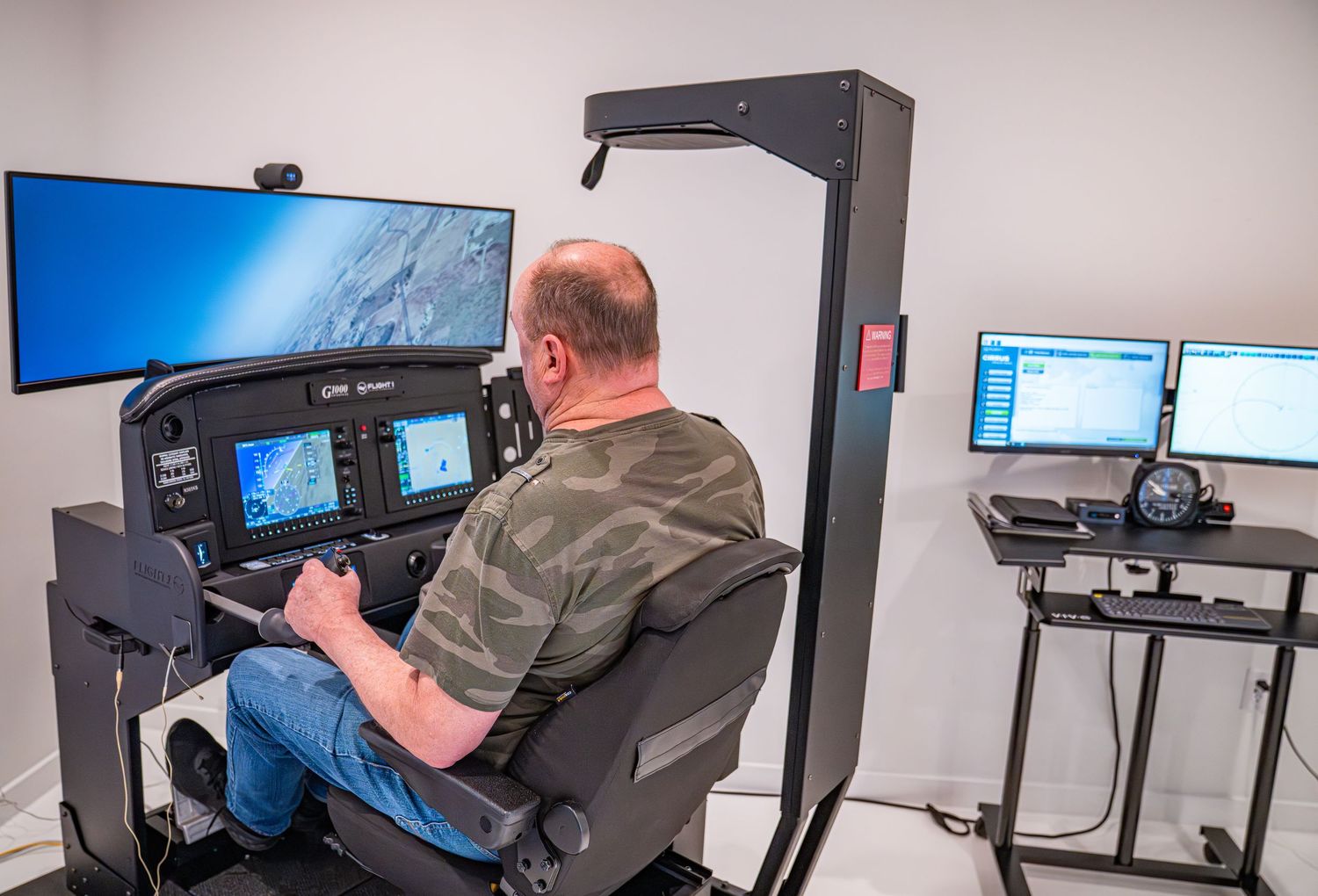 Flight simulator setup with multiple screens and control panels in training room.