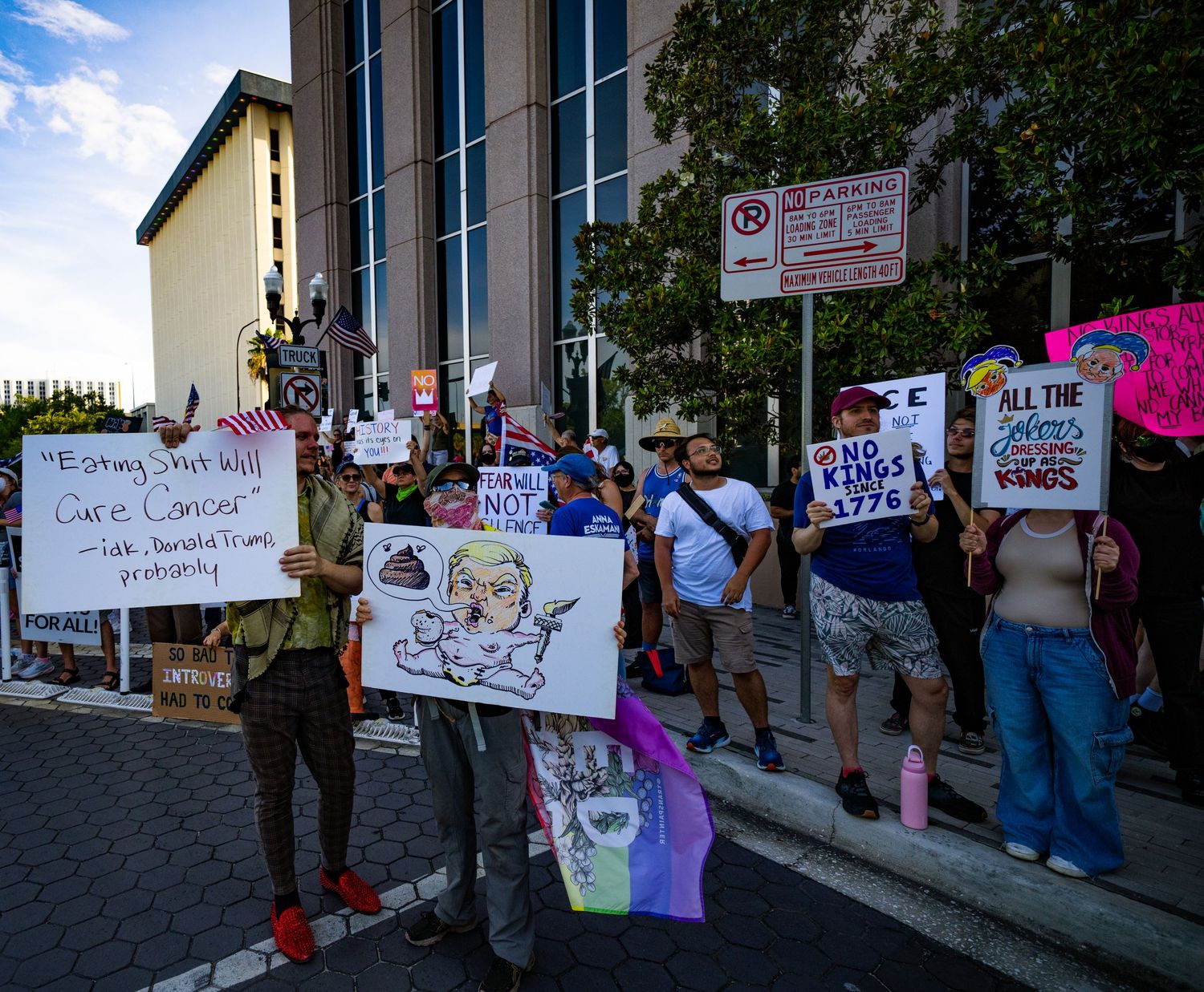 Protesters hold signs and gather outside a building during a demonstration.
