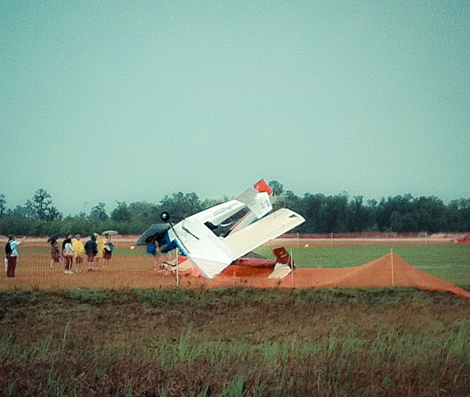A small aircraft crash sequence showing a plane flipping over in a grassy field during an emergency landing.