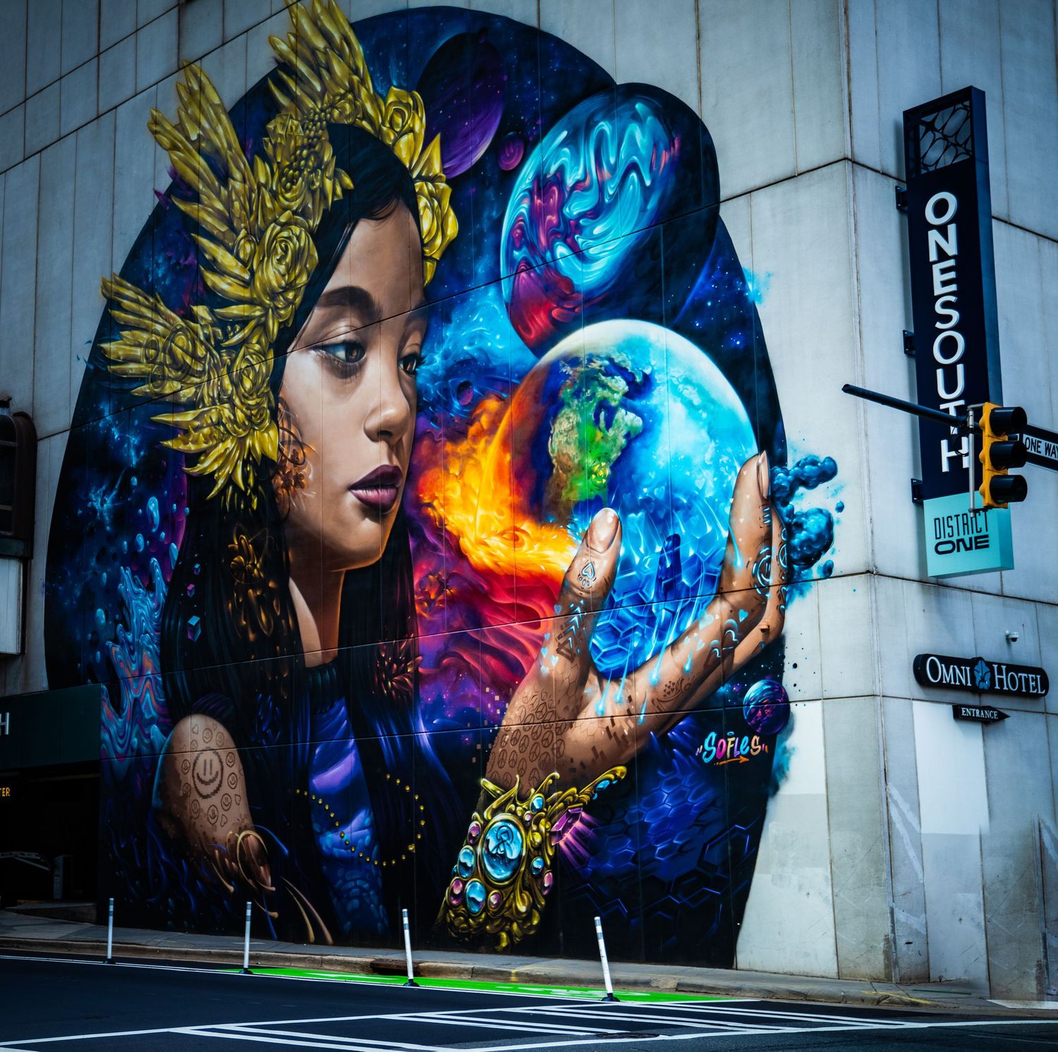Street art mural featuring cosmic and space themes with vibrant colors against modern architecture.