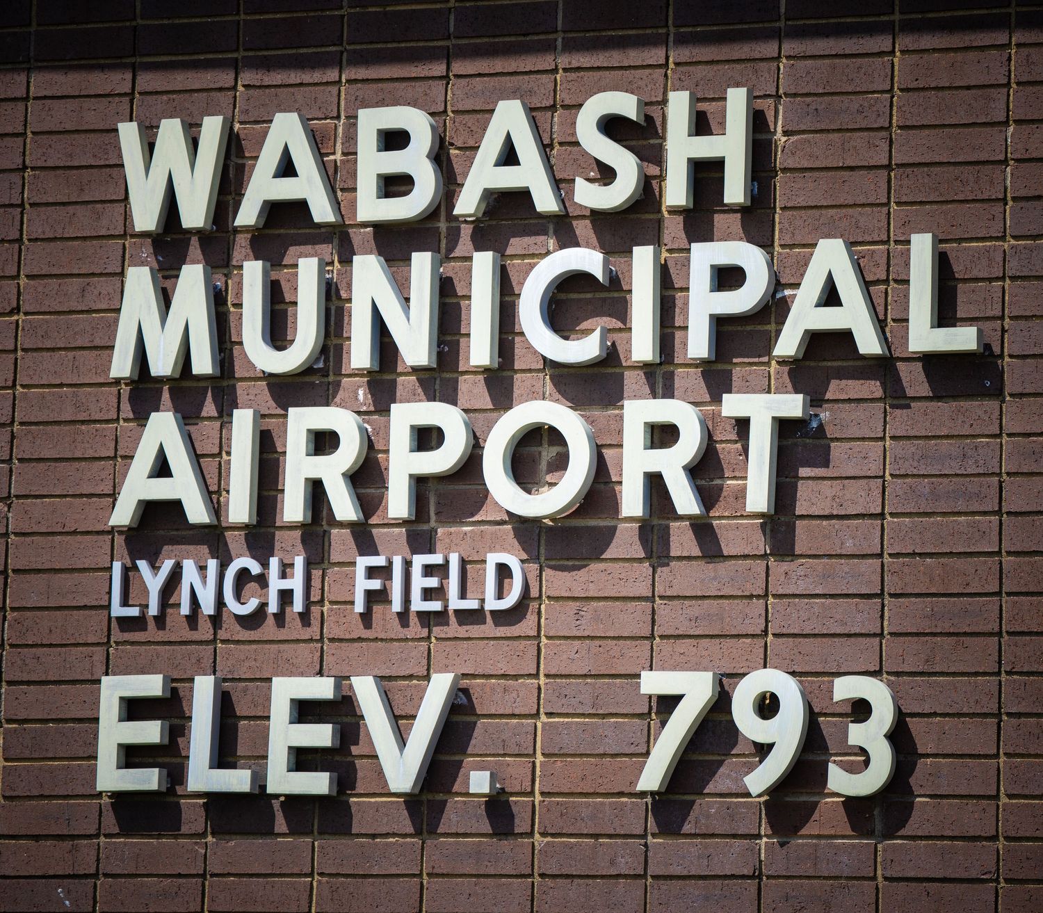 Wabash Municipal Airport Lynch Field elevation sign on brick wall.