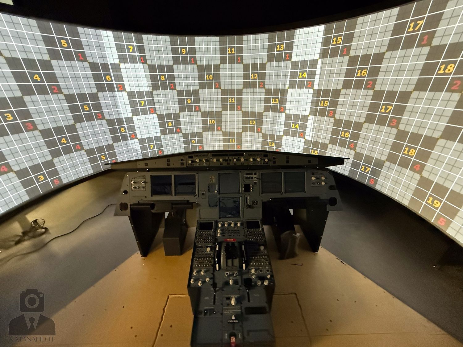 Flight simulator cockpit control panel with mosaic-tiled wall background.