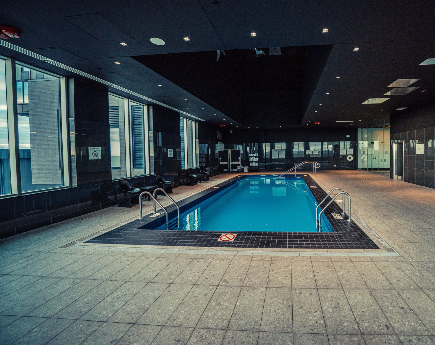 Indoor swimming pool with modern design features and large windows.