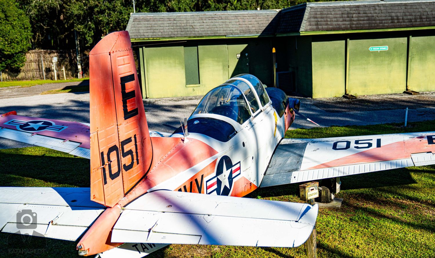 Vintage aircraft and military planes displayed on grass at an aviation museum.