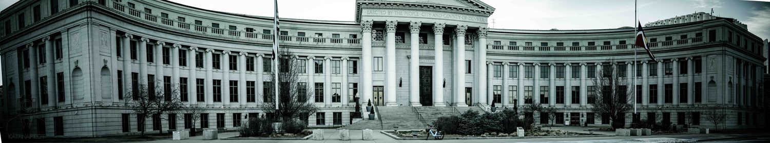 A panoramic black and white view of a neoclassical government building with columns and symmetrical architecture.