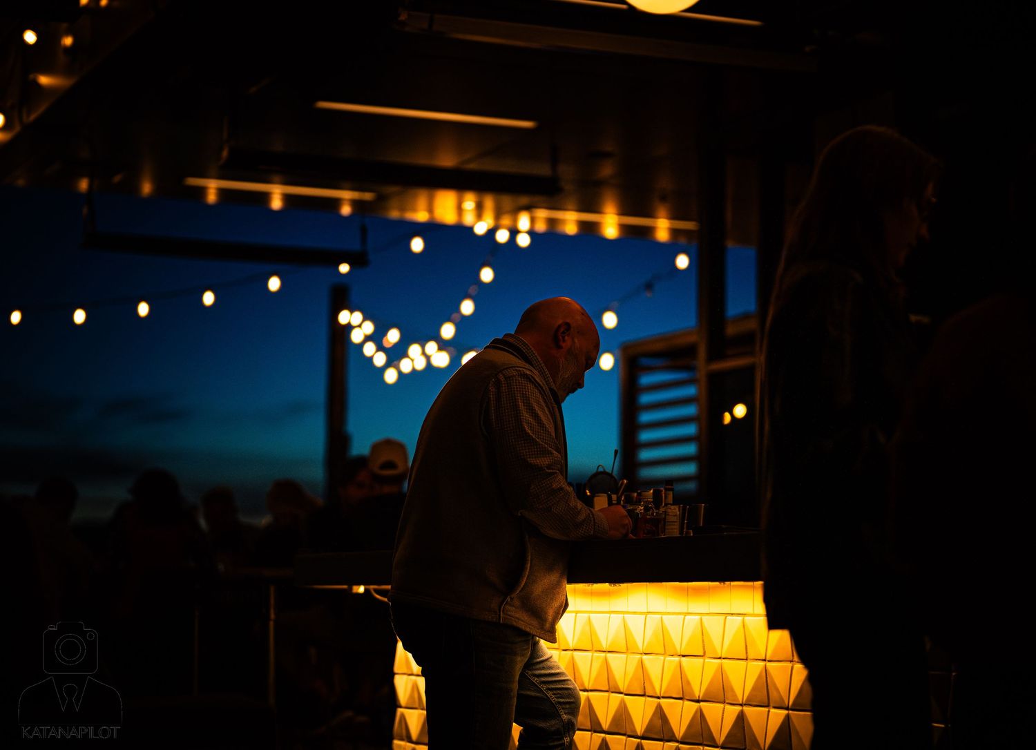 String lights illuminate an outdoor event space at night creating a warm and festive atmosphere.