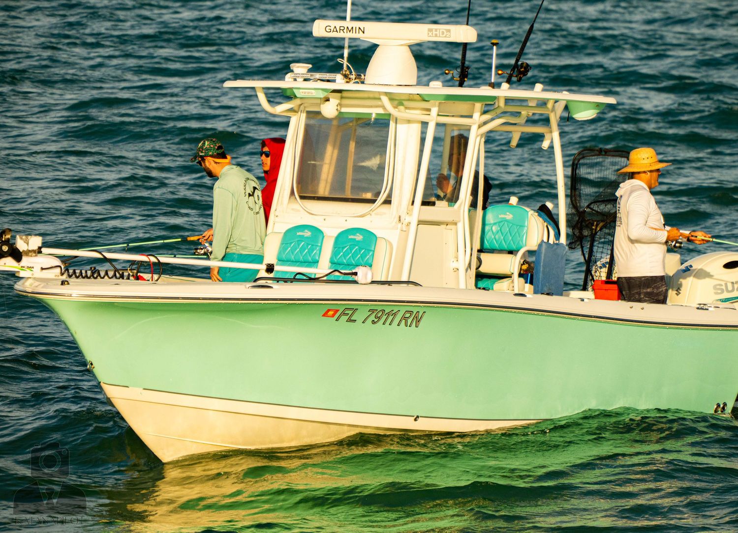 A line of mint green and white fishing boats floating on dark blue ocean waters.