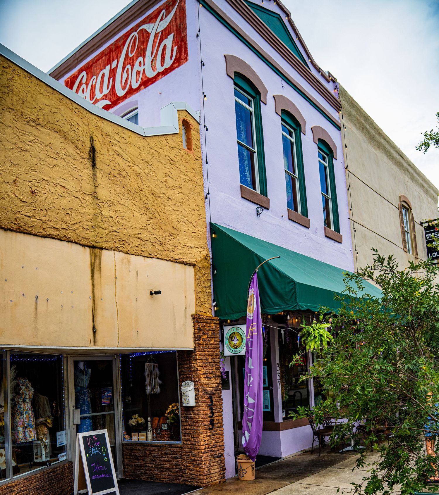 Commercial strip with Coca-Cola signage and yellow stucco walls along a shopping center.
