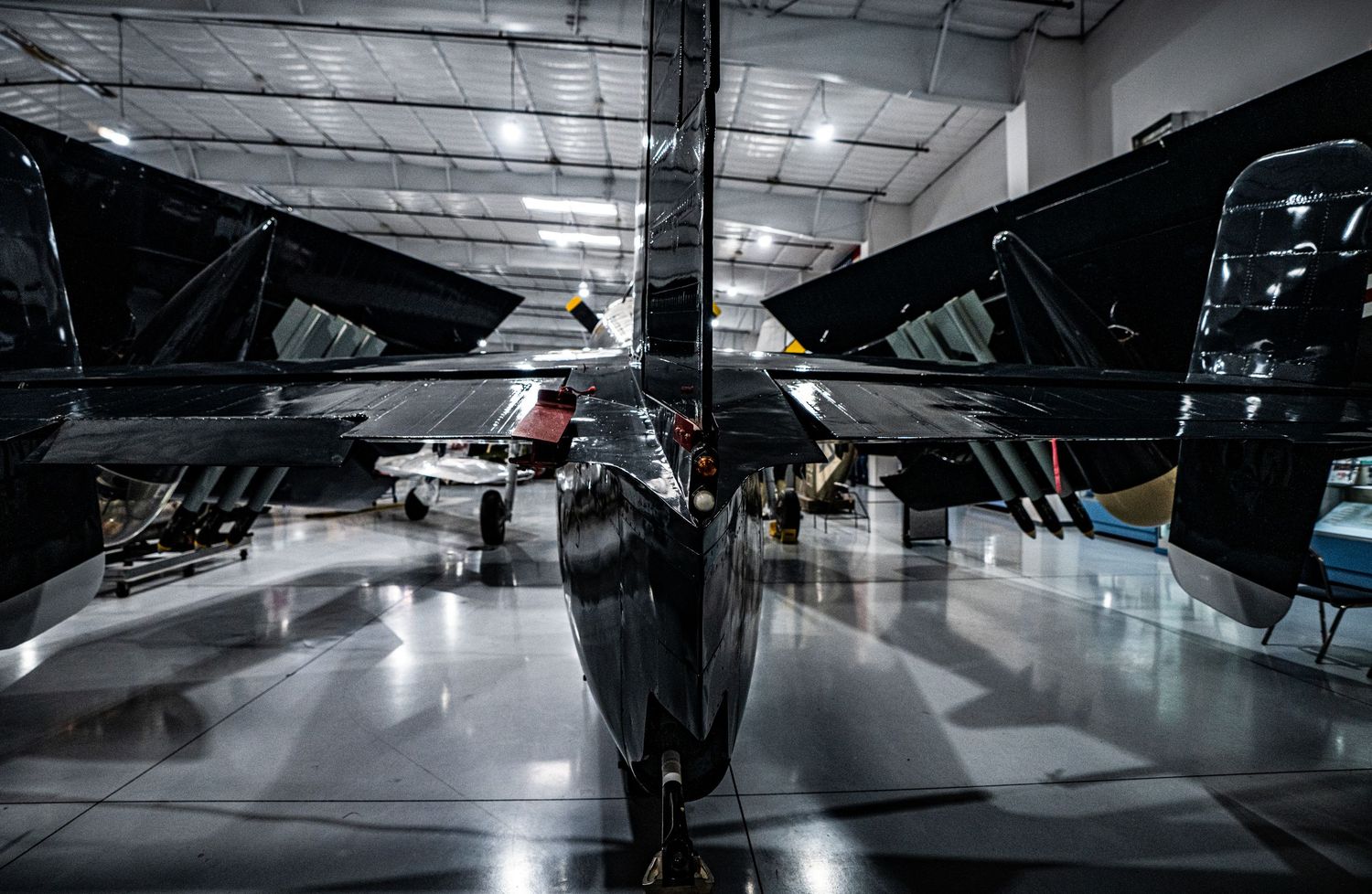 Sleek black military aircraft displayed from below in a well-lit aviation museum hangar.