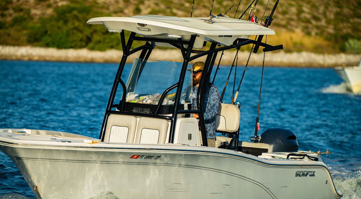 A series of fishing boats moored in a marina with blue water and sunny skies in the background.