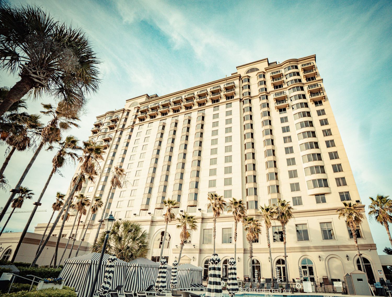 Panoramic sequence showing a luxury beachfront hotel with palm trees against a turquoise sky in Florida.
