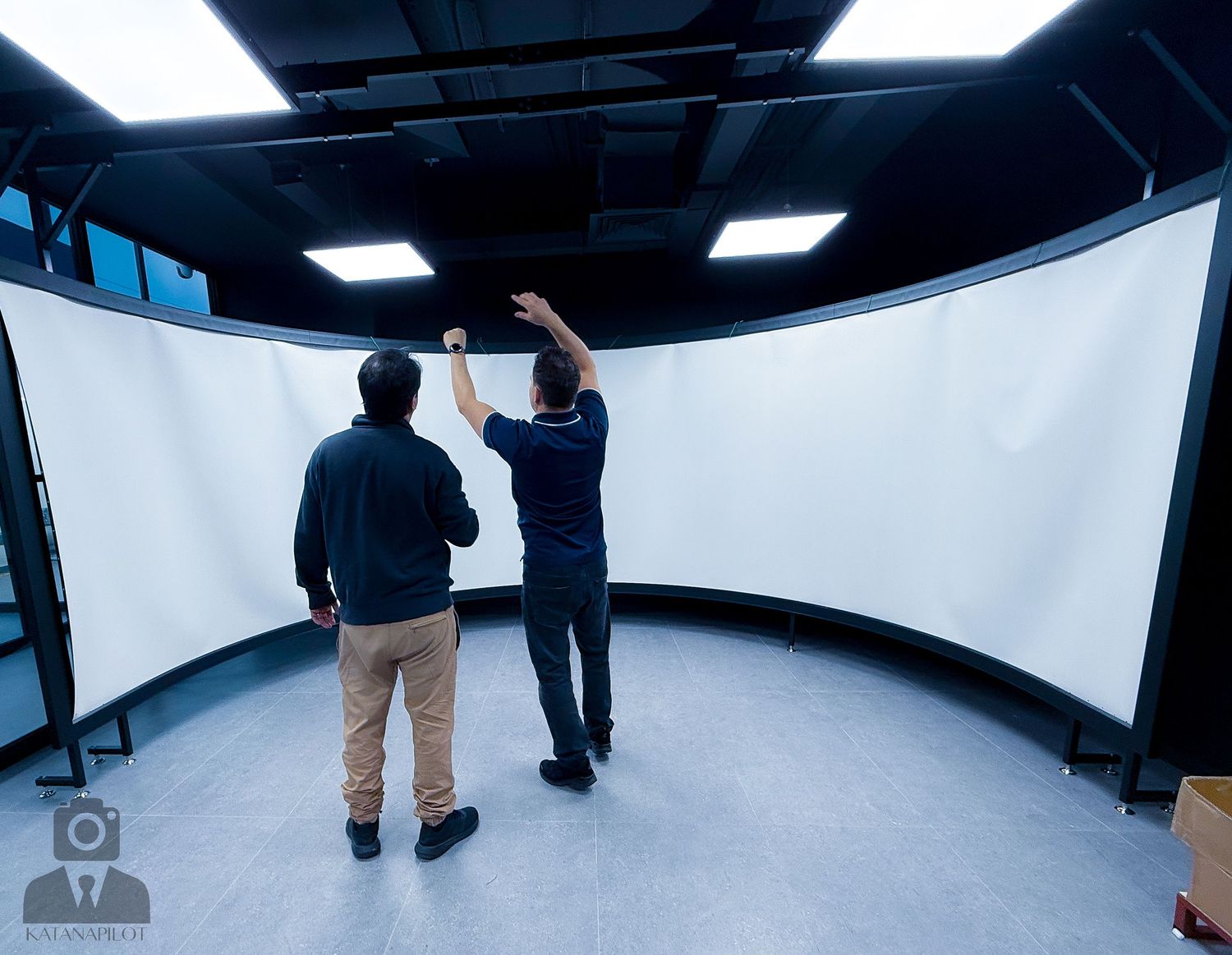 Wide-angle view of an empty flight simulator room with curved walls and overhead lighting.