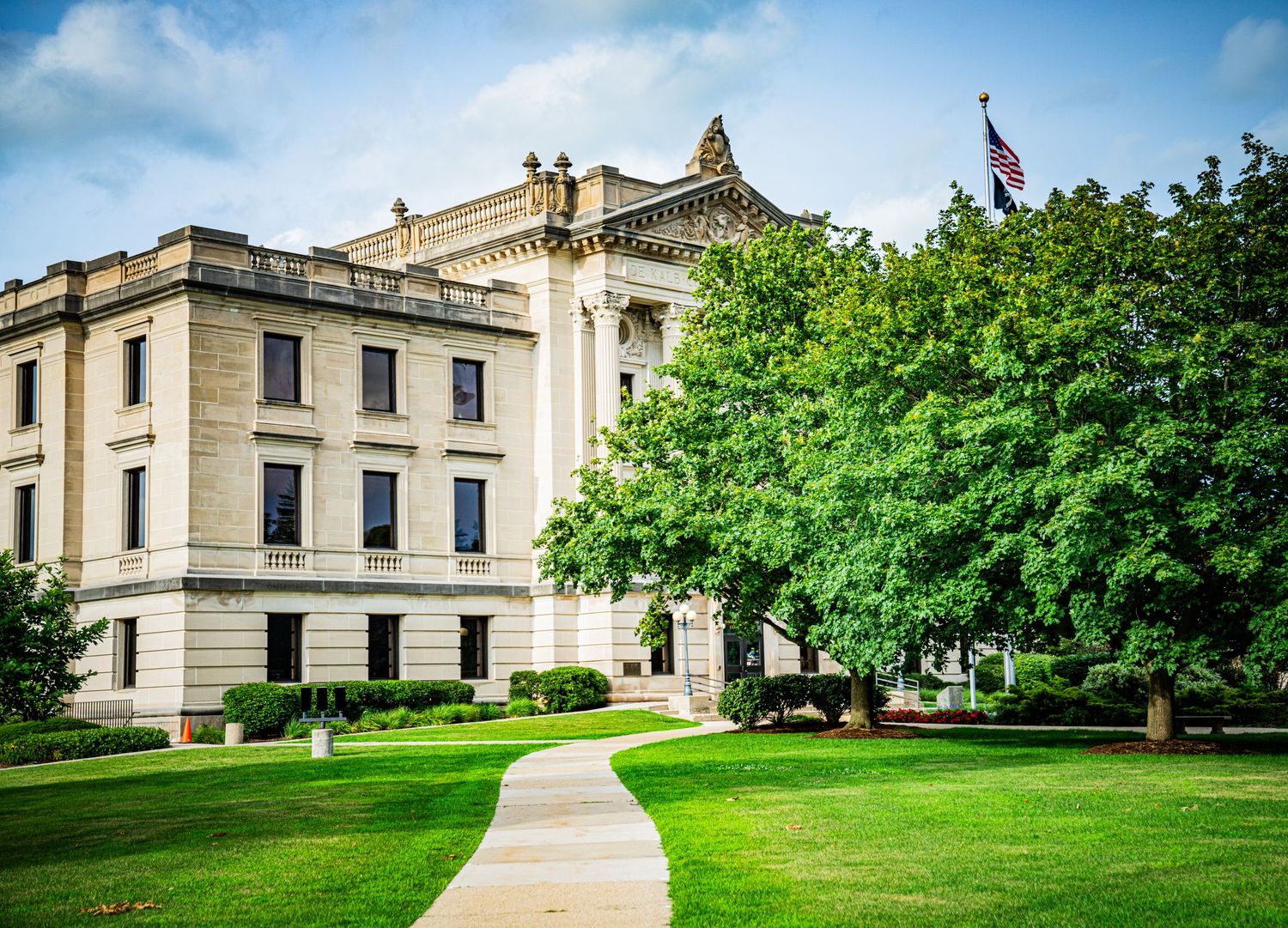 Neoclassical government building with columns and manicured lawns shown from various angles.