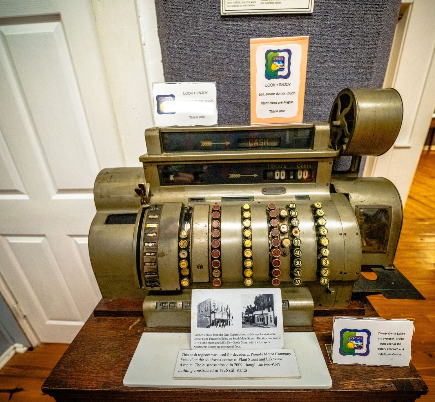 Antique mechanical calculator or adding machine displayed on museum pedestal.