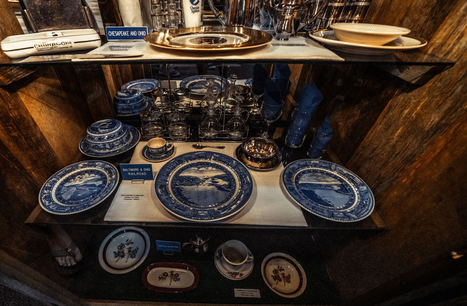 Panoramic view of vintage blue and white collector plates arranged on wooden shelving.