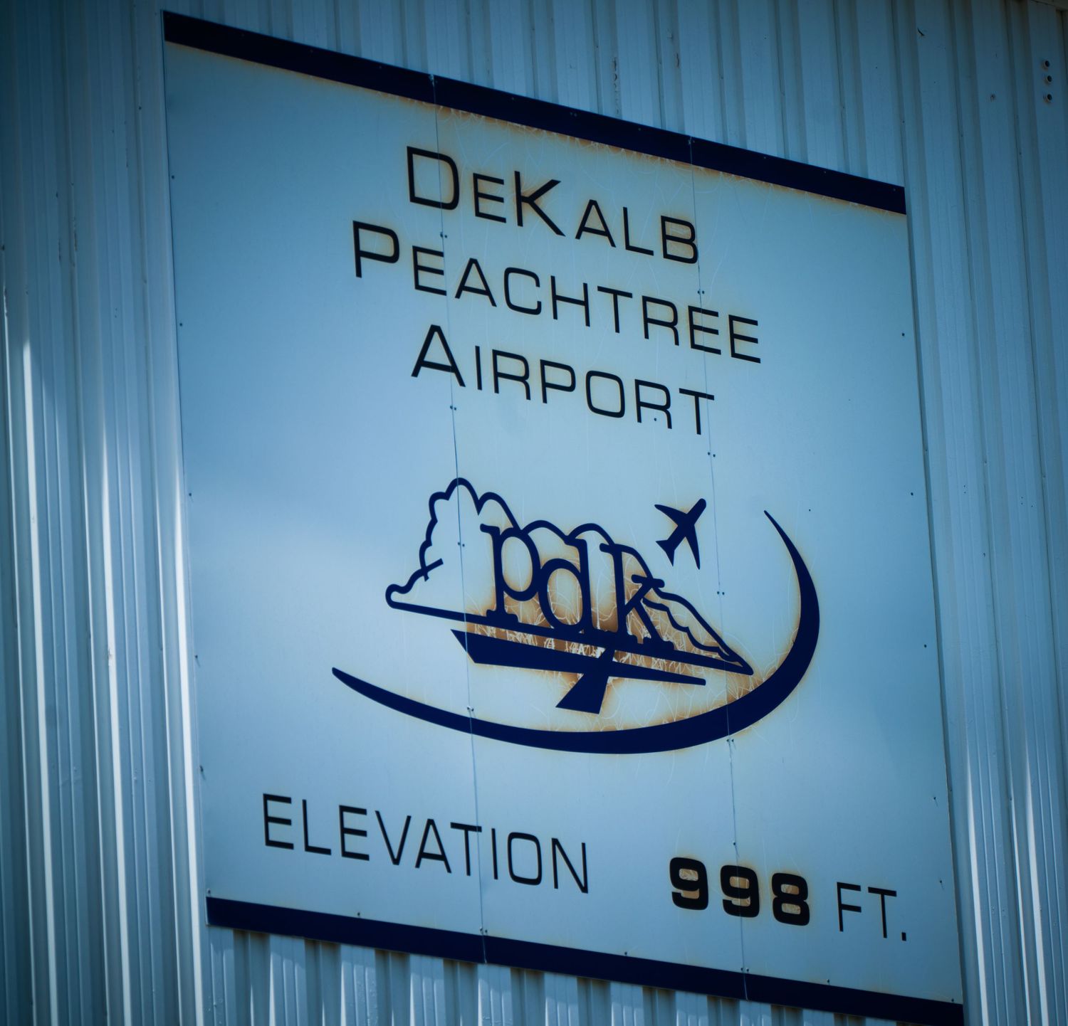 Airport signage showing elevation and aircraft symbols on metal wall.