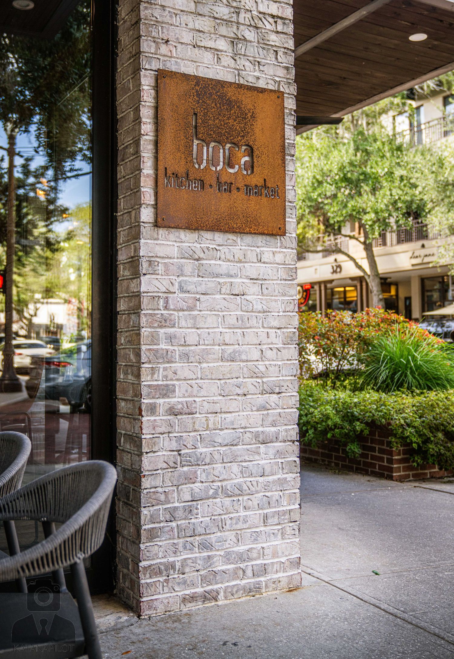 Whitewashed brick exterior of a modern building with covered patio seating area.