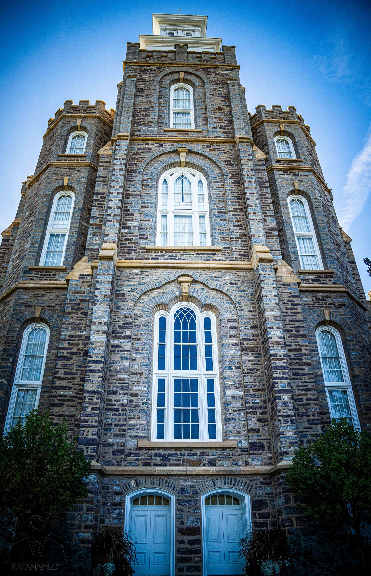 Historic stone church building with tall arched windows and decorative architectural details.