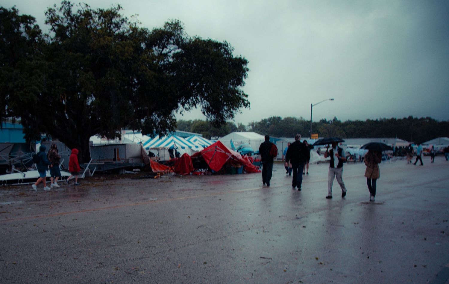 A panoramic view of a beach area with red tents and umbrellas set up along the shoreline on a cloudy day.