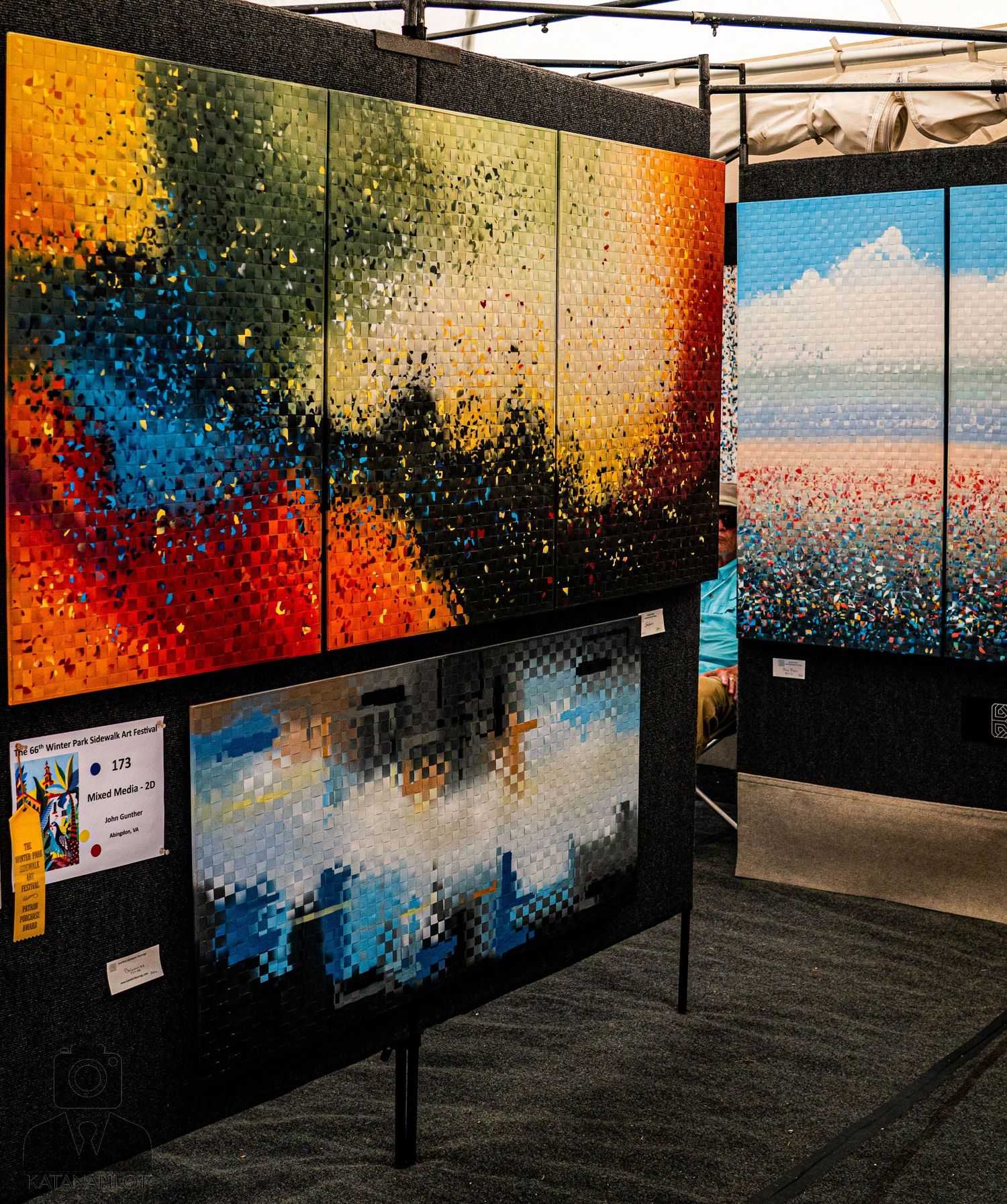 Abstract art installation featuring colorful pixelated landscapes displayed in a dark gallery space.