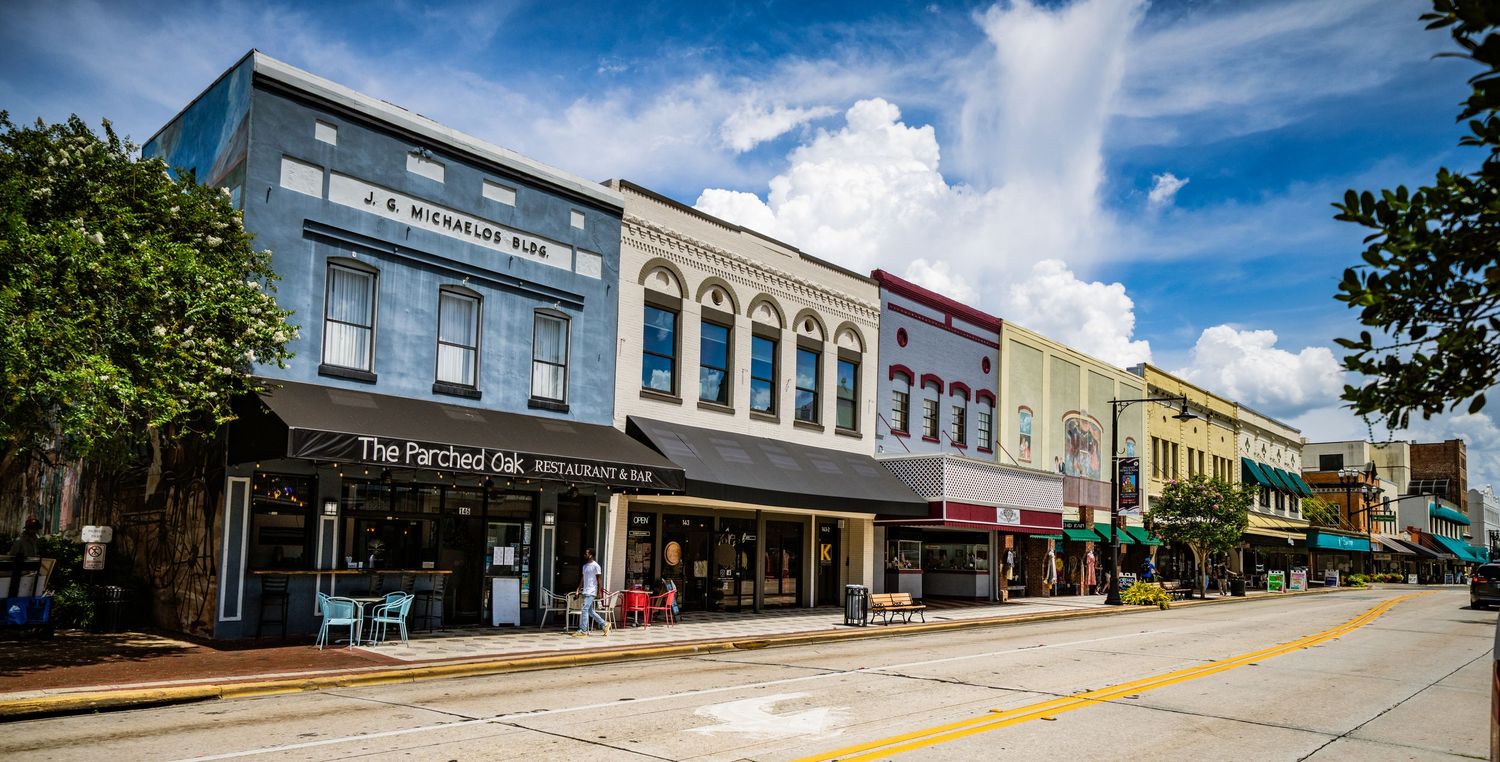 Row of historic commercial buildings with colorful storefronts along a downtown street.