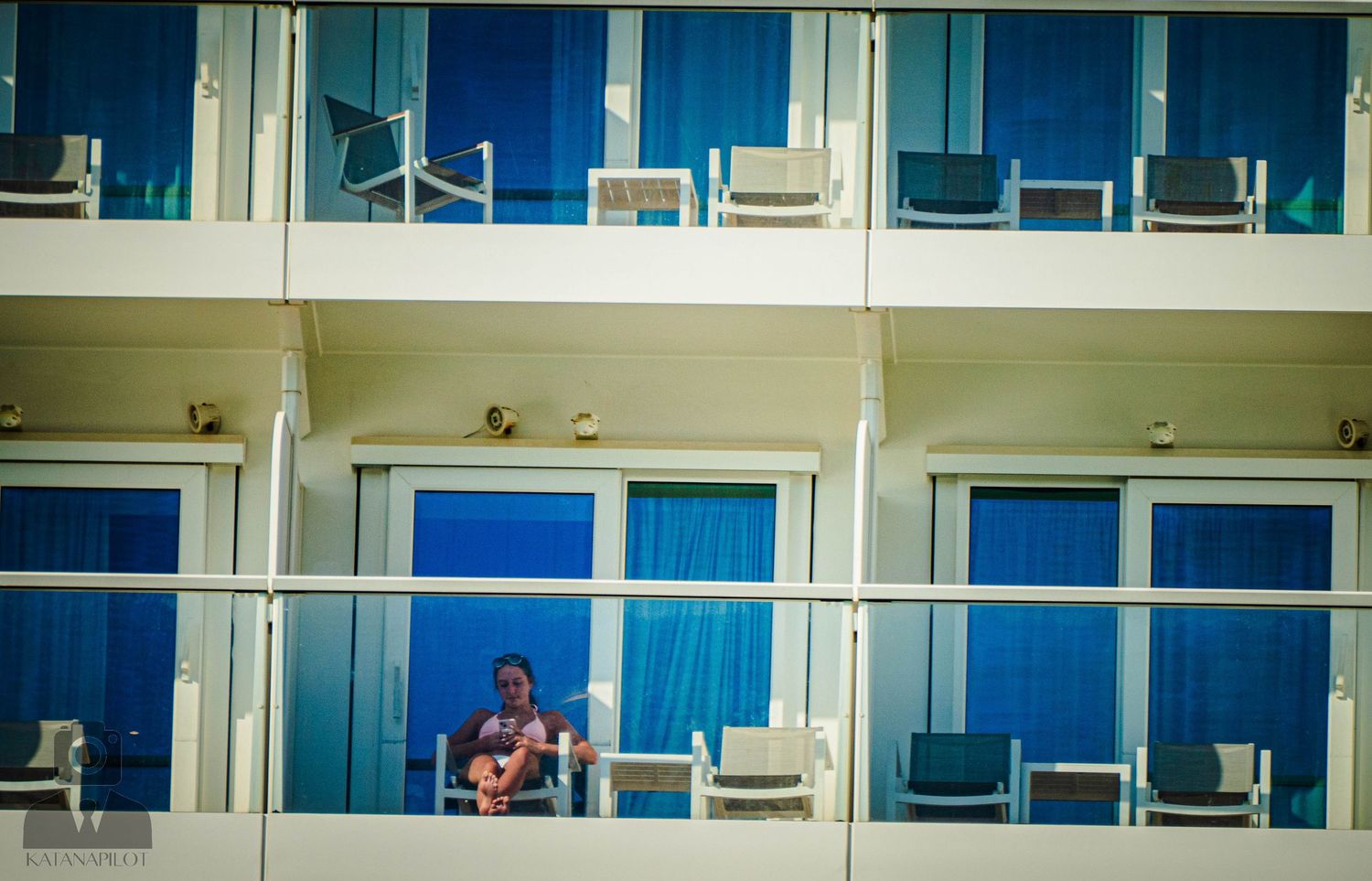 A panoramic view of a modern building complex with blue-tinted windows and balconies overlooking the water.