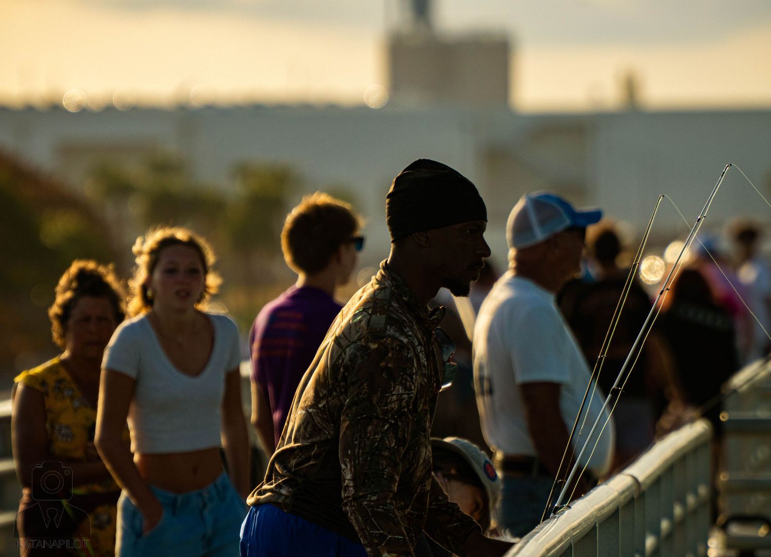 Silhouettes of people standing outdoors against a golden sunset sky with long shadows stretching across the ground.